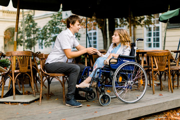 Pretty young woman on a wheelchair enjoying some good company on a date with her handsome man at a cafe outdoors in the city