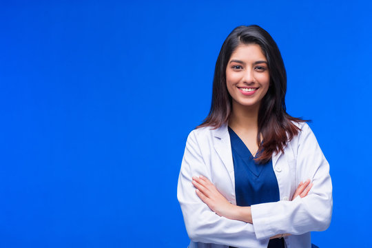 Medical concept of Asian beautiful female doctor in white coat with stethoscope, waist up. Medical student. Woman hospital worker looking at camera and smiling, studio, blue background
