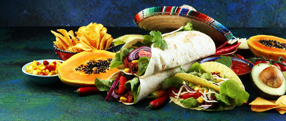Mexican food, including tacos, guacamole, nachos and pepper on rustic table