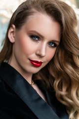 Portrait of a beautiful blonde girl with red lips and evening makeup, wavy hair wearing a black velvet jacket. Healthy, clean skin. Close-up. Advertising, commercial design.