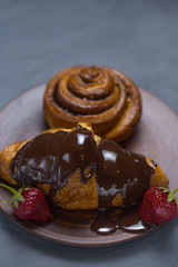 Cinnamon roll chocolate croissant strawberries lie on a dish on the table