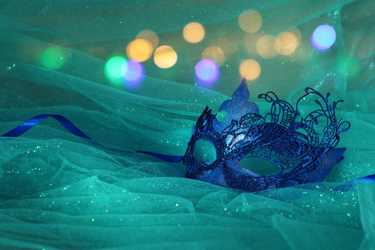 Photo of elegant and delicate blue Venetian mask over mint chiffon background
