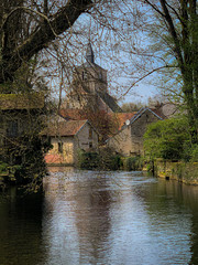 Picturesque river view with the village church seen through the over hanging trees.