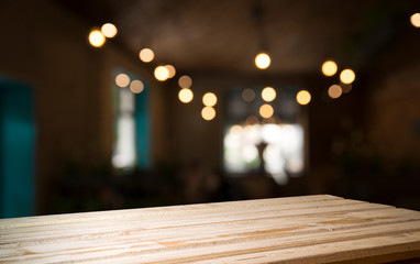 Empty wood table top on blur light gold bokeh of cafe restaurant in dark background
