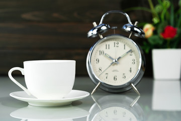 Coffee cup and alarm clock on table