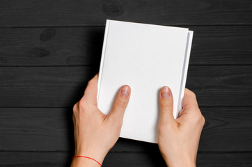 Men's hands holding closed book with blank cover on light background