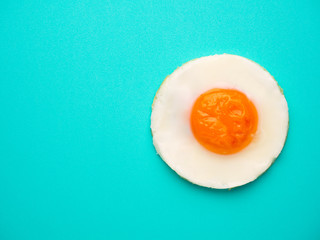 Perfect circle fried egg on blue-green background