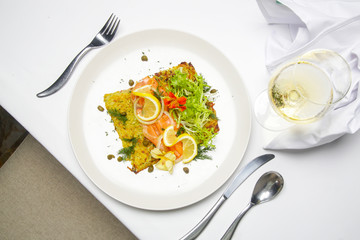 Smoked salmon with potato fritter, decorated with green salad and lemon slices. Exquisite dish. Creative restaurant meal concept.	