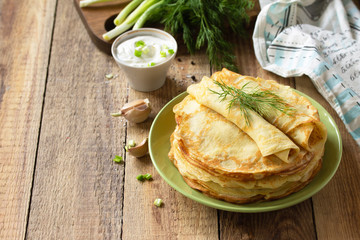 Potato pancakes, not sweet, served with garlic cream sauce on rustic wooden table. Copy space.