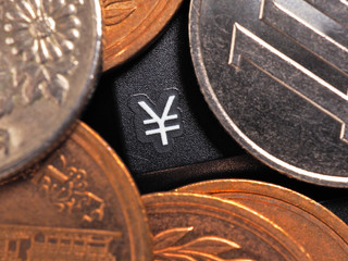 The symbol of the yen. Japanese money coins lie on a black computer or laptop keyboard around a button with this sign. Online trading, payments and transfers. Macro