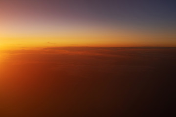 Beautiful view of sunset sky above clouds from airplane.