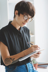 Portrait of young business woman in glasses taking notes in notebook.