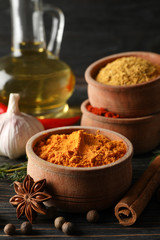 Bowls with spices and ingredients on wooden background, close up