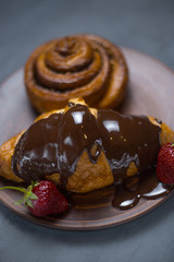 In the foreground chocolate croissant strawberries in the background cinnamon roll