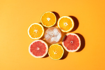 Citrus fruits and glass with ice in sunlight. Making summer drink