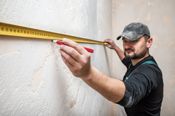 builder measures the distance of the tape measure