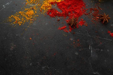 Different types of spices on a dark stone background, view from the top