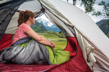 woman sits in tent with sleepbag in Norway