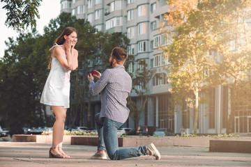 Young man proposing to his beloved outdoors