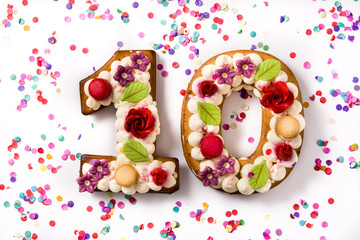 Number ten cake decorated with flowers  and macarons isolated on white background.	