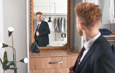 Handsome man trying on stylish clothes in dressing room