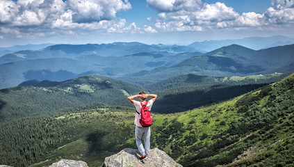 tourist hiker alone standing on top of a mountain, skyline forest summer outdoor