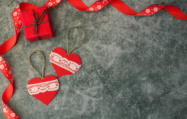 Holiday background for Valentine's Day on a gray cement background with hearts, gifts and a ribbon.