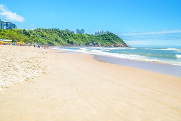 Beautiful Brazilian beach of the Paulista coast on a sunny day. Sunbathers, sunshades and the wonderful view at Praia do Tombo beach - Guaruja SP Brazil.