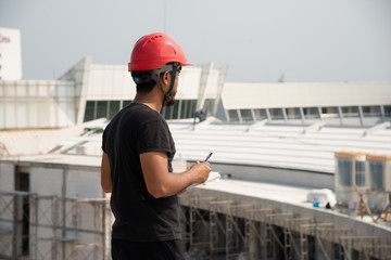 Black bearded engineer wear red hard hat and black working suit make decision in construction site