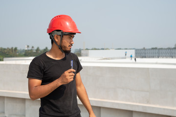Black bearded engineer wear red hard hat and black working suit make decision in construction site