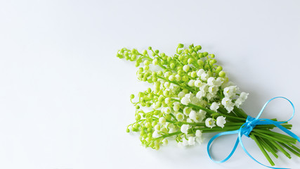 bouquet of delicate fragrant lilies of the valley, tied with a blue ribbon top view. festive...