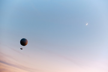 Balloon and moon in the sunset sky.