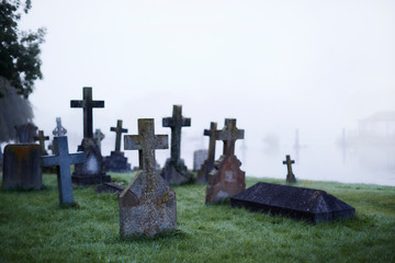 Crosses on gravestones in ethereal foggy cemetery
