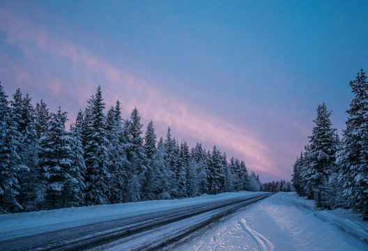 Remote winter road through snow covered forest trees, Lapland, Finland