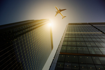 Airplane flying over highrise buildings, travel concept