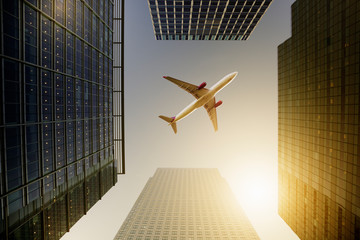 Airplane flying over highrise buildings, travel concept