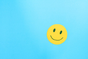 Yellow face smiling on blue background.