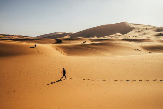 Man walking in sunny, sandy desert, Sahara, Morocco