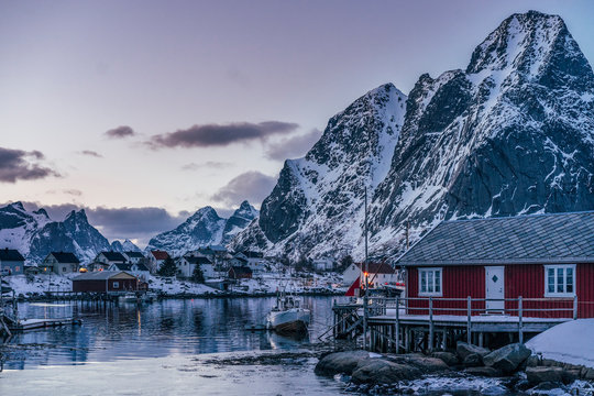 Tranquil fishing village below snowy mountains, Reine, Lofoten Islands, Norway