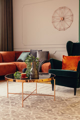 Emerald green wing back chair with orange pillow in luxury living room interior