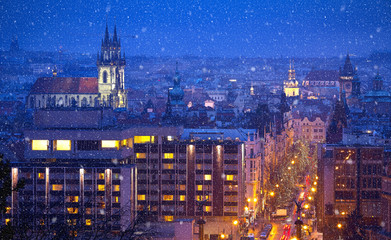 Prague Czech Republic. View at nighttime winter town with falling snow tower and broach cathedral. Illuminated with illumination street and Church of Our Lady Before Tyn aerial view.