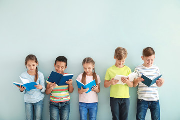Cute little children with books on color background