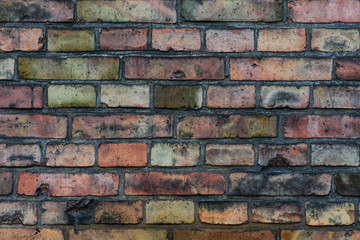 Close-up photo of a very old red brick wall, on which defects were partially manifested due to long time and weather conditions, partially changed color