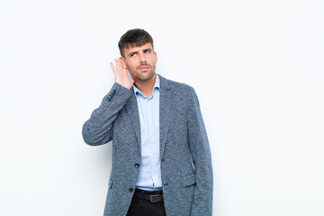 young handsome man looking serious and curious, listening, trying to hear a secret conversation or...
