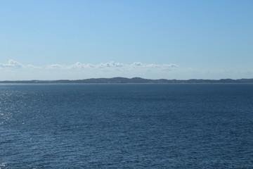 blue sea with mountain silhouettes on horizon and infinite blue sky