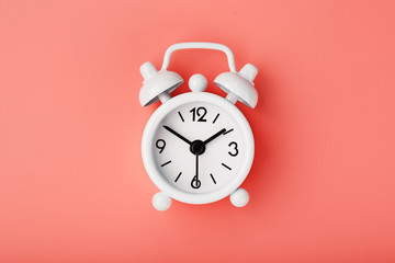 White retro alarm clock on pink background. Concept of time with free space for text.