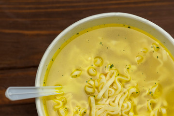 Retro style wooden background. On it is a plate of paper. Cooking fast pasta. White plug.