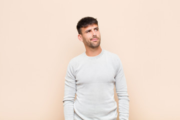 young handsome man looking puzzled and confused, wondering or trying to solve a problem or thinking...