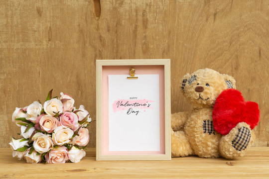 Mockup Picture frame and cute bear holding red heart with Bouquet of pink roses on rusty wood. Valentines Day Background concept with copy space. Mock up with photo frame for your picture or text