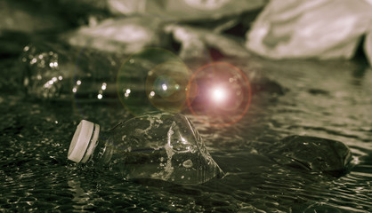 environment pollution concept image with floating plastic bottles on the riverbank
